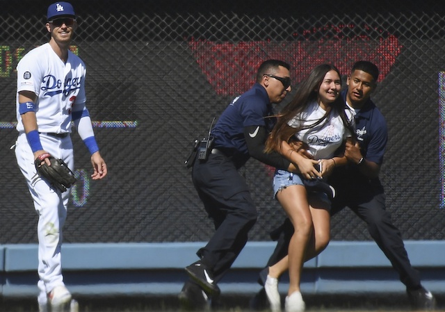 Los Angeles Dodgers right fielder Cody Bellinger is hugged by a fan on the field at Dodger Stadium