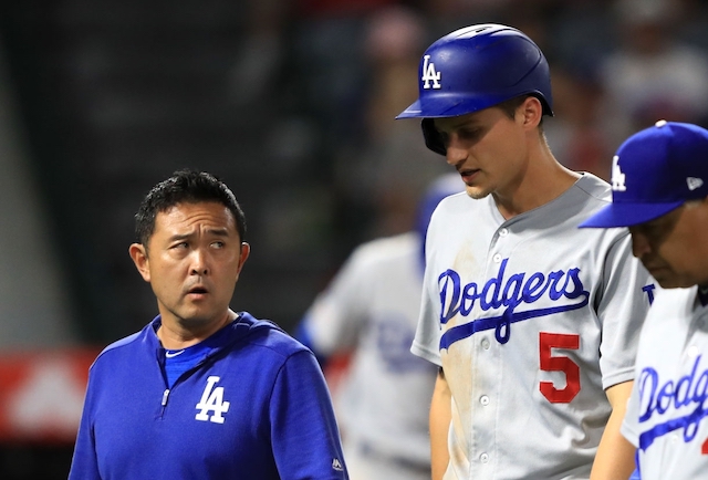 Los Angeles Dodgers manager Dave Roberts and a team trainer walk off the field with Corey Seager after his hamstring injury